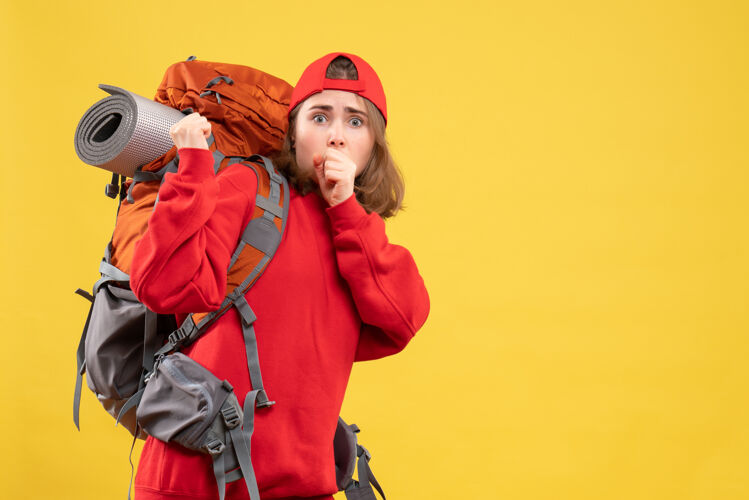 帽子前视图困惑的旅行者妇女在红色背包站在黄色的墙上背包站工作
