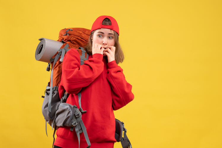 背包正面图困惑的女旅行者背着背包站在黄色的墙上工作表情站立