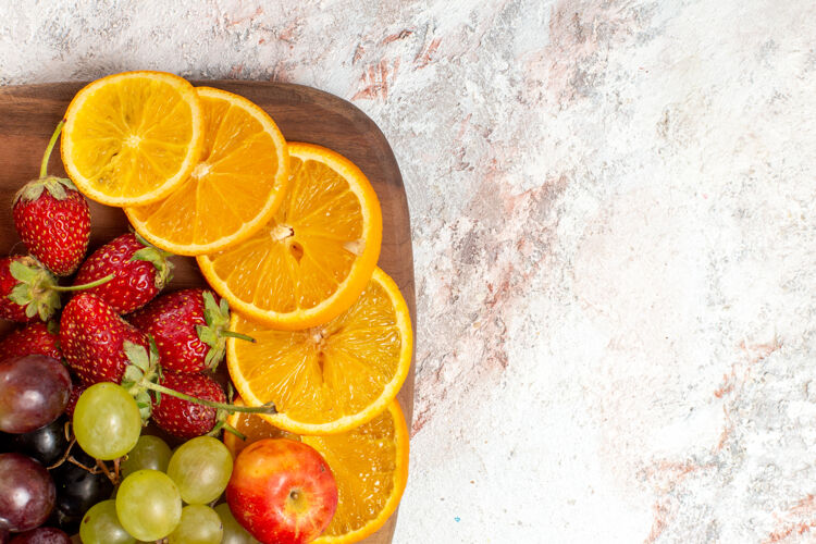 果汁白色表面上新鲜水果成分橙子葡萄和草莓的俯视图柑橘食品水果