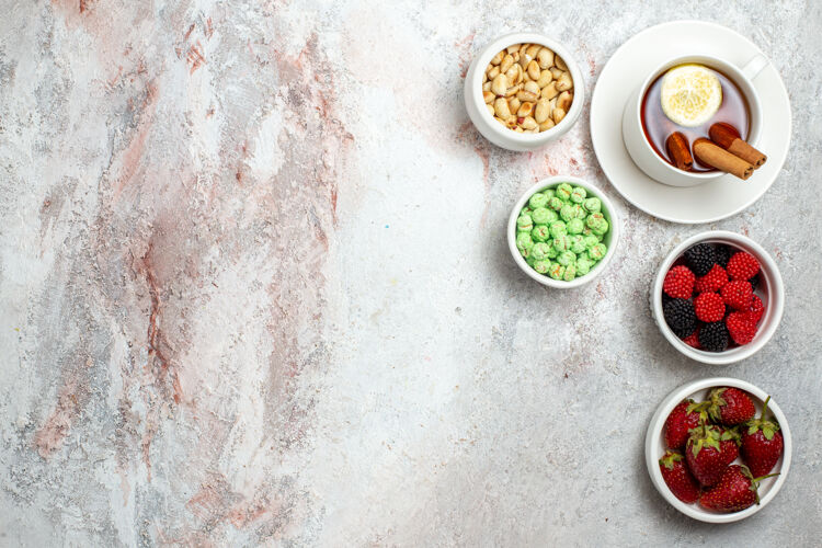 食物白色表面上有草莓和坚果的茶杯俯视图浆果盘子美味