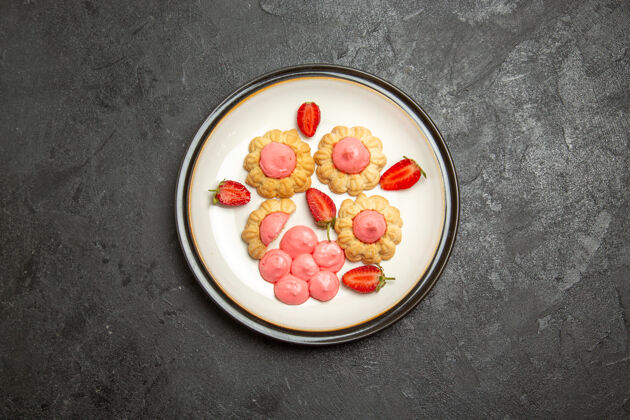 草莓美味的糖饼干与草莓果冻在灰色的表面俯视图糖葡萄干浆果