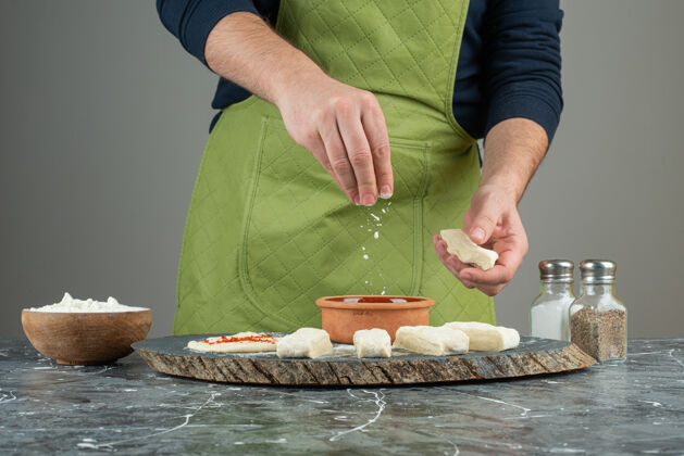 面粉男人戴着手套在大理石桌上做面团生的自制面包师