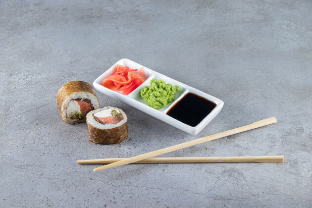 美味寿司卷以金枪鱼 芥末 生姜和酱油为石头背景米饭新鲜卷
