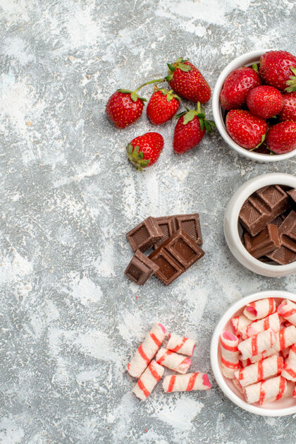 食品顶视图碗草莓巧克力糖果和一些草莓巧克力糖果在右边的灰白色的桌子新鲜餐桌可食用水果