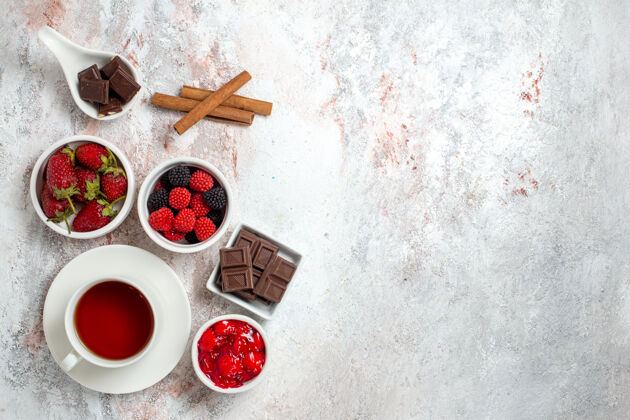 盘子一杯草莓果酱茶的俯视图和白色表面上的壁龛餐桌茶杯子