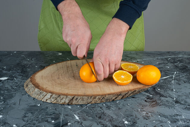 各种男人的手在大理石桌上切橘子混合橙子围裙