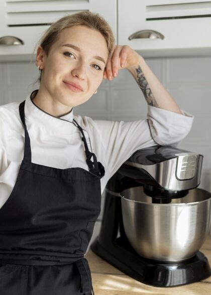 职业中镜头笑脸女人摆姿势搅拌机烹饪橱柜