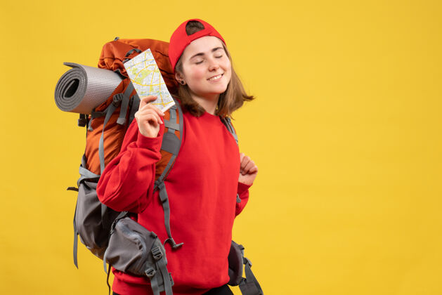 成人前视图满意的女徒步旅行者与红色背包举行地图帽子背包快乐