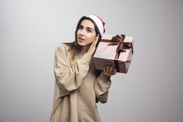 表情一个年轻的女人为一份圣诞礼物而兴奋礼物盒子圣诞老人