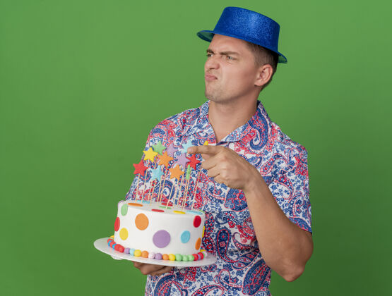 蓝色未被释放的年轻人党看一边戴着蓝帽子拿着蛋糕点在一边孤立的绿色举行年轻点