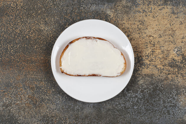 吐司在白色盘子上放一片带酸奶油的烤面包片正餐食物涂抹