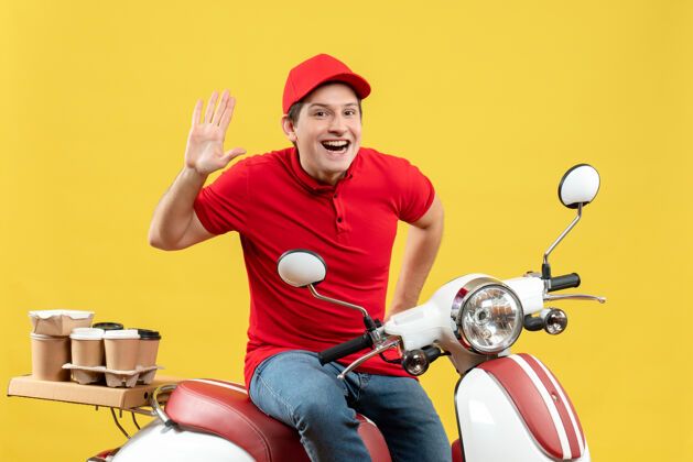 成人一个微笑的年轻人身穿红色上衣 戴着帽子 在黄色背景上展示十张订单的正面图年轻人交付坐着