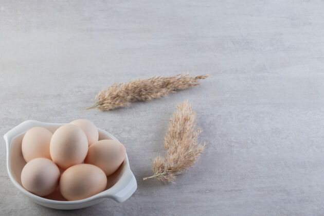 蛋壳石头桌上放着一碗白色的生鸡蛋美味鸡肉农场