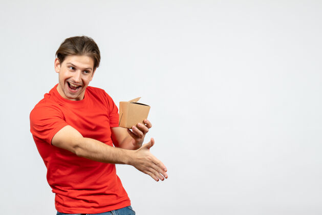 小学生正面图是一个穿着红色上衣的快乐年轻人拿着一个小盒子 在白色背景上欢迎某人肖像盒子红色