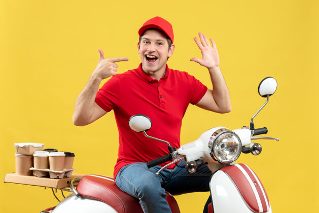 成人顶视图自信满意的年轻人穿着红色衬衫和帽子 在黄色背景下传递命令送货红色年轻人