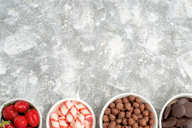 新鲜上半部分是草莓 糖果 麦片 巧克力 在灰白色的地面下面种子胡椒研磨