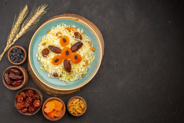 早餐美味煮熟的普洛夫米饭的顶视图 在黑暗的表面上 盘子里有不同的葡萄干烹饪葡萄干食物