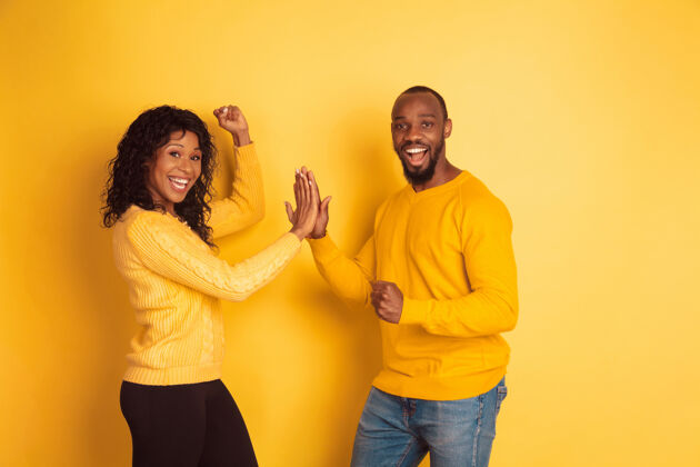 微笑年轻感性的非裔美国人 穿着鲜艳的休闲服 在黄色背景上摆姿势美丽的情侣人类情感的概念 面部表情 关系 广告团队合作指向一起非洲