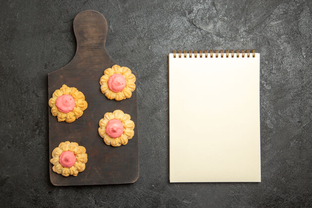 饼干灰色表面上草莓奶油小甜饼的俯视图质地花卉茶