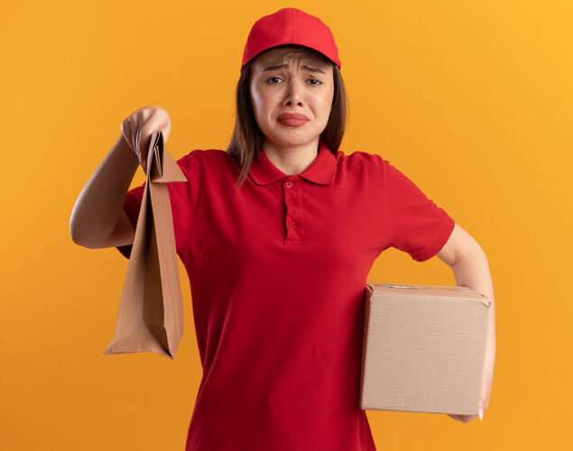 包装一个穿着制服的悲伤漂亮的女送货员手里拿着橙色的纸包和名片盒橘子制服纸