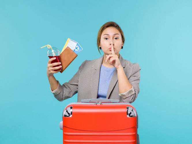 旅行正面图：度假中的女性拿着果汁和机票在蓝色背景下航行飞机度假旅游海上票蓝色视图