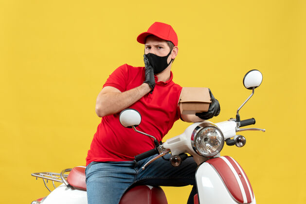 摩托车俯视图：一个穿着红色上衣 戴着帽子 戴着手套 戴着医用面罩 坐在滑板车上拿着订单的快递员运动车辆手套