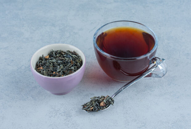 温暖一碗干茶叶和一杯用勺子放在大理石上的茶风味叶子美味