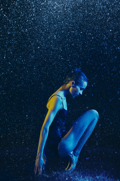 明亮年轻的女芭蕾舞演员在水滴和浪花下表演白种人模特在霓虹灯下跳舞迷人的女人芭蕾舞和当代舞蹈概念创意艺术照片表演运动平衡