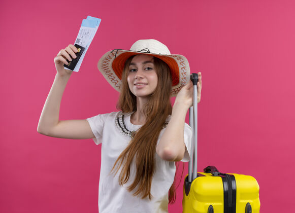 帽子高兴的年轻旅客女孩戴着帽子拿着信用卡 机票和手提箱就孤立的粉红色空间旅客粉色女孩