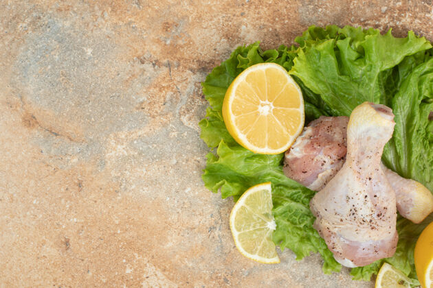 鸡肉生鸡腿配柠檬片和生菜放在大理石表面生的莴苣柠檬