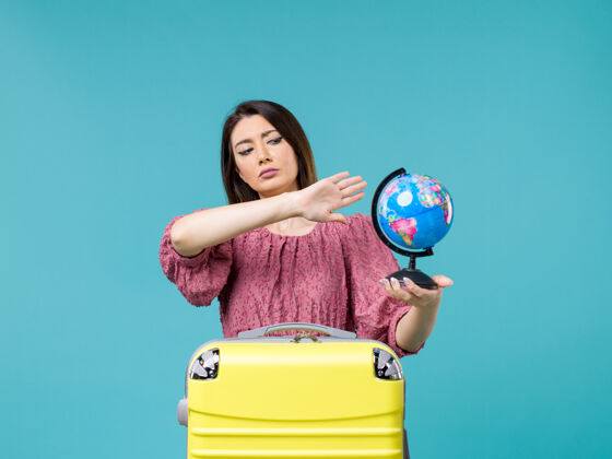 度假前景度假中的女性手持小地球仪在蓝色的背景海上度假之旅夏日女性之旅运动微笑地球仪
