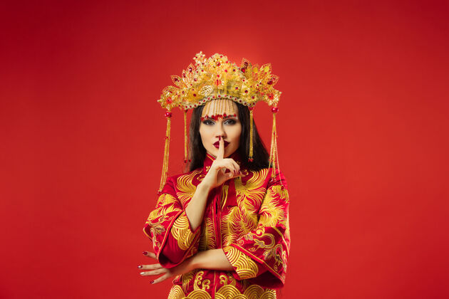 服饰中国传统的优雅女子在摄影棚的红色背景美丽的女孩穿着民族服装中国新年 优雅 优雅 表演者 表演 舞蹈 女演员 服装的概念服饰优雅微笑