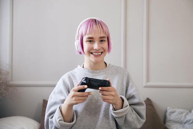 房子粉红色头发的女人在玩电子游戏娱乐室内享受