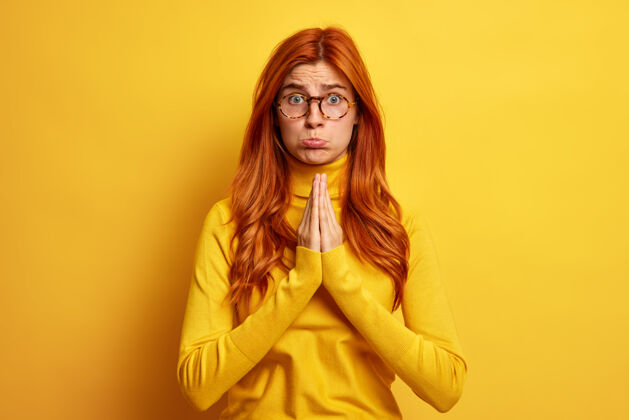 情绪照片中 一个绝望的 不高兴的红发女人双手合十 做着祈祷的姿势 穿着休闲的高领毛衣 神情哀求着道歉站姜祈祷