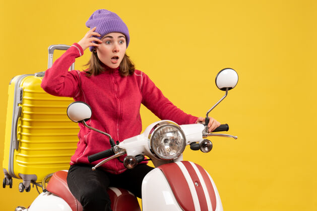 前面前视图困惑的年轻女孩骑着轻便摩托车抱着她的头球轻便摩托车人