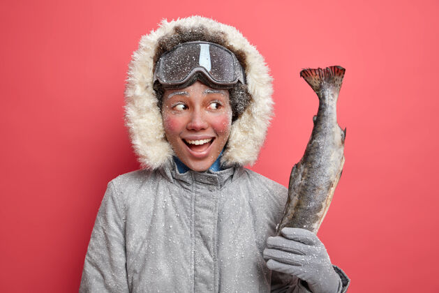 鱼快乐美丽的女人在冬天被霜冻覆盖 在寒冷的霜冻天去钓鱼 在户外穿着暖和的外套度过空闲时间快乐肖像兜帽
