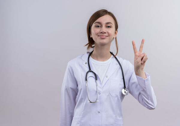听诊器高兴的年轻女医生穿着医疗袍和听诊器做和平的迹象与复制空间女性复制和平