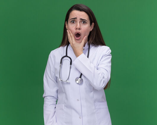 医生焦急的年轻女医生穿着带听诊器的医用长袍 托着下巴 看着绿色的摄像机女焦虑医疗