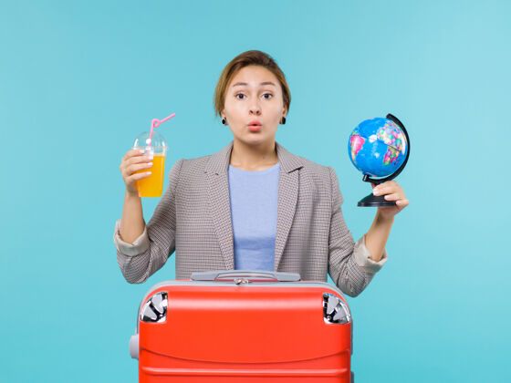 旅行前景：度假中的女性手持新鲜果汁和地球仪在蓝色的背景海上度假旅行女人人成人