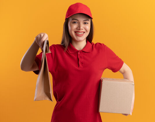 微笑身着制服的微笑漂亮的送货员手里拿着橙色的纸包和名片盒制服橘子纸