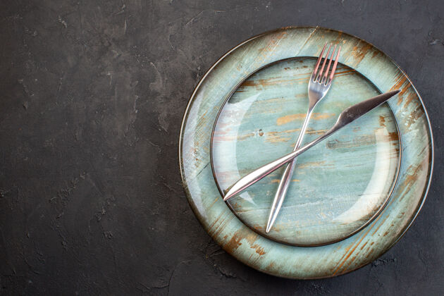 刀顶视图蓝色板与叉和刀在黑暗的表面内深色食物餐具