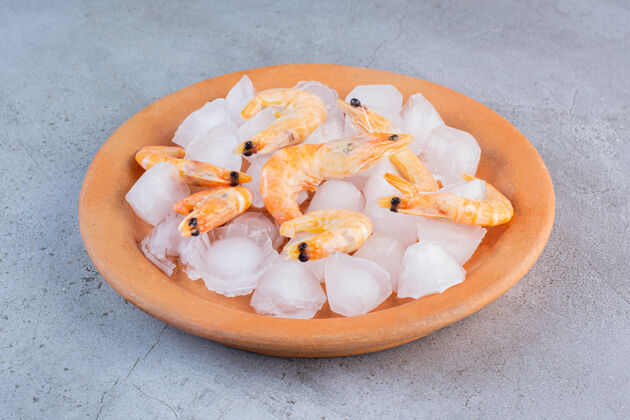 生的美味的虾仁放在石头表面的橙色盘子里美味料理新鲜