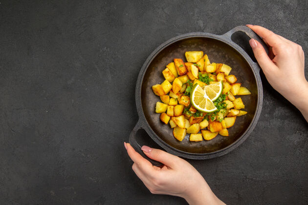 一餐顶视图美味的煎炸土豆内锅柠檬片在黑暗的表面柠檬平底锅里面