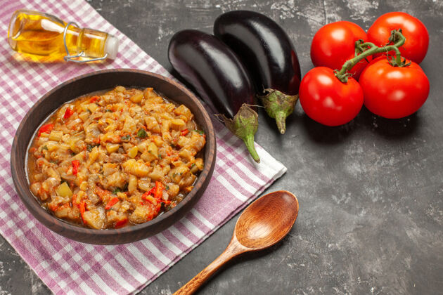 油顶视图烤茄子沙拉碗木勺西红柿茄子油瓶在黑暗的表面木头菜肴食物