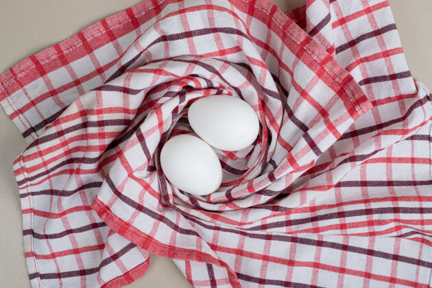 未煮熟的两个新鲜的鸡蛋放在桌布上生的食物鸡肉