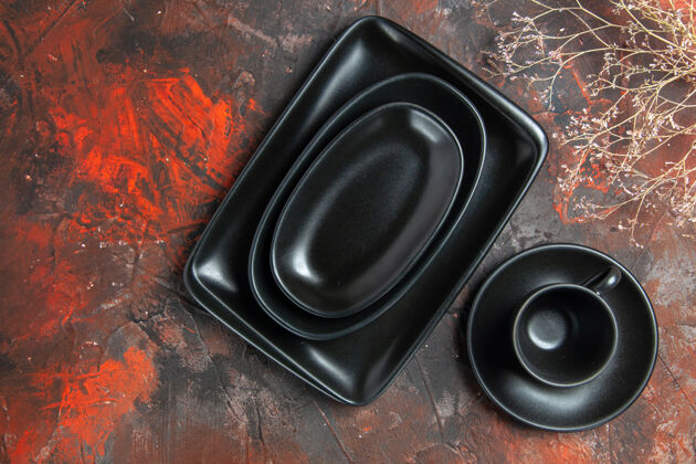 音频黑色椭圆形和矩形盘子的顶视图暗红色表面上的黑色杯子和碟子音乐设备电器设备