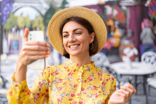 沟通街头彩墙上穿着黄色夏装的女人的户外时尚写真未来女性科技
