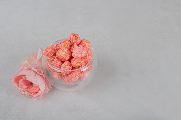 垃圾食品玫瑰花冠和一杯爆米花放在大理石桌上鲜花玉米碗