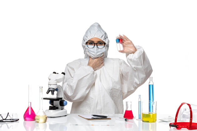 实验室外套正面图穿着特殊防护服的女化学家拿着空瓶子在白色桌子上健康病毒化学病毒面具化学专业