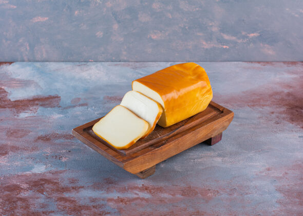 美味长方形的奶酪片放在大理石表面的木板上膳食美食膳食